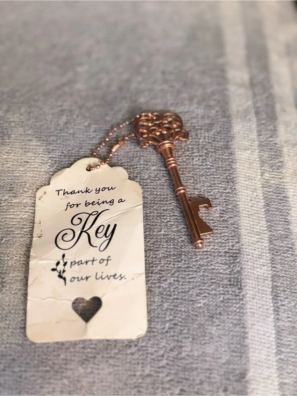 Gold tone Key-shaped pendant with card.